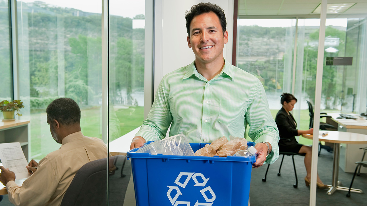 Businessman smiling whilst holding a tub for recycling