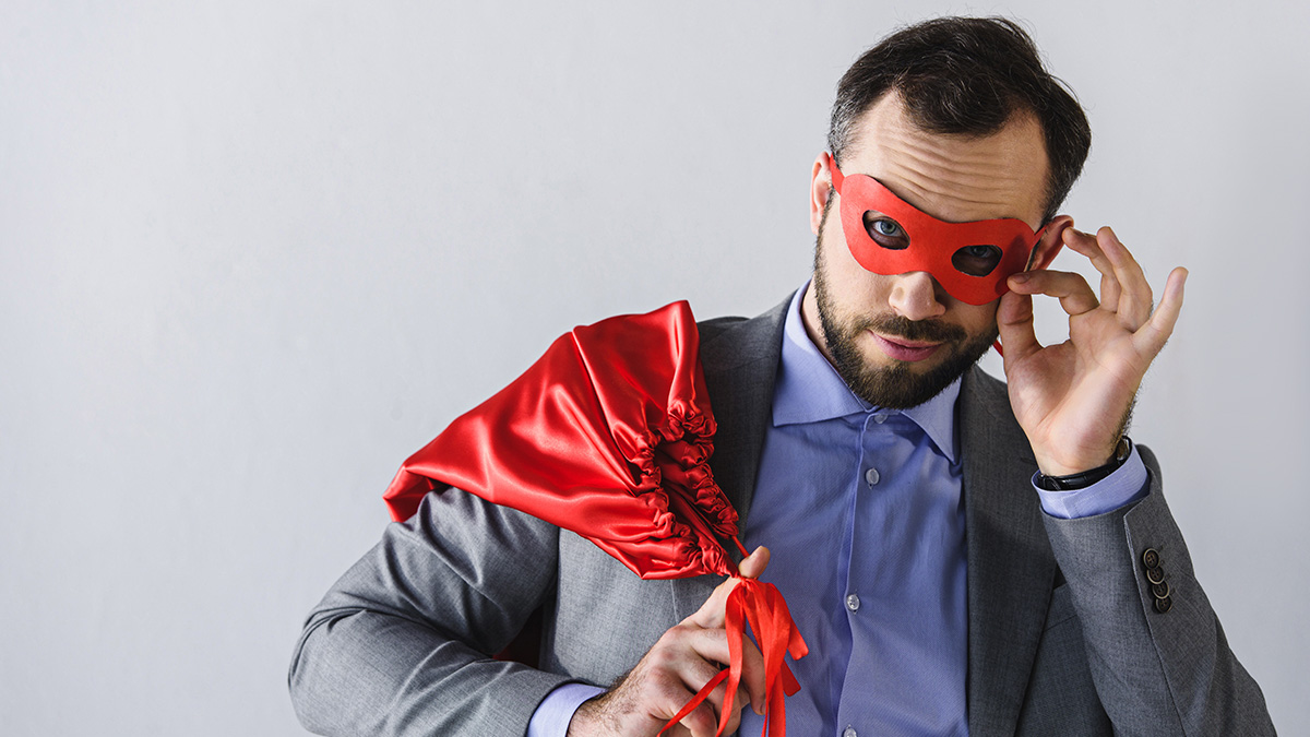 Man in a business suit with a red mask and cape