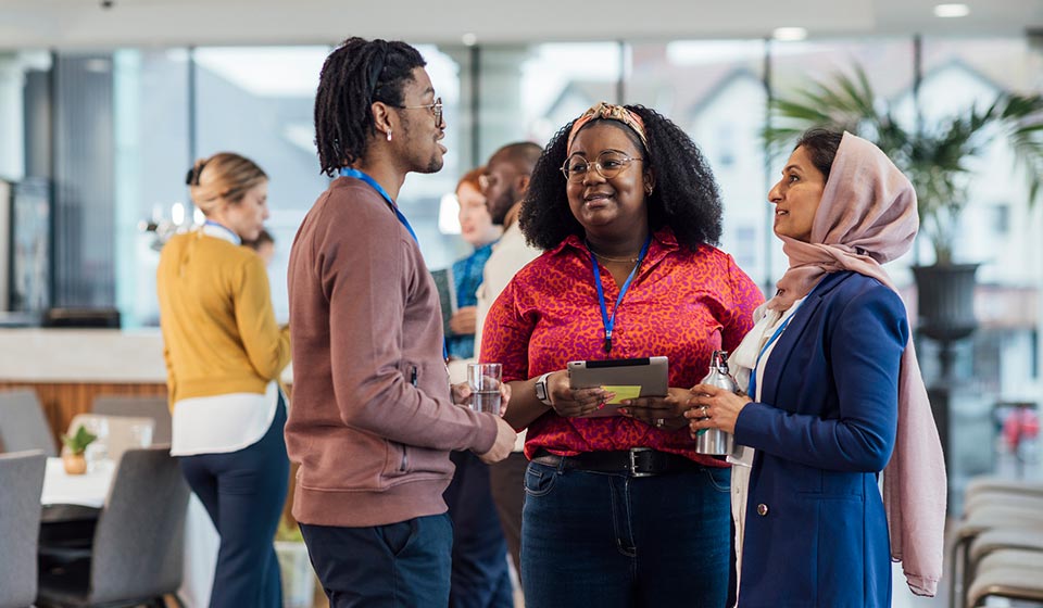 A wide angle view of a group of mixed age professionals who are taking advantage of a networking opportunity at a business conference